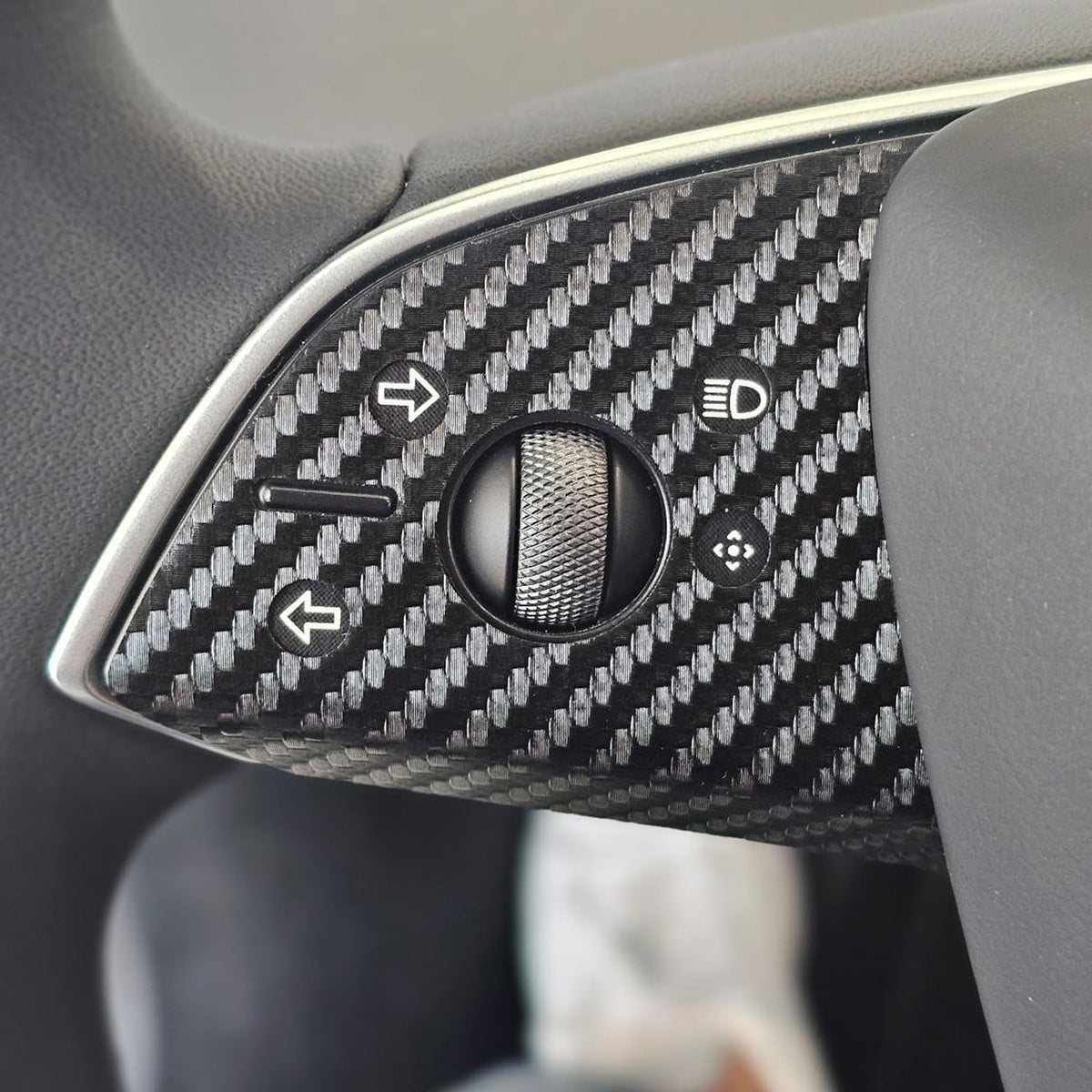 Carbon fiber skin applied around the steering wheel buttons of a Tesla Model Y Juniper